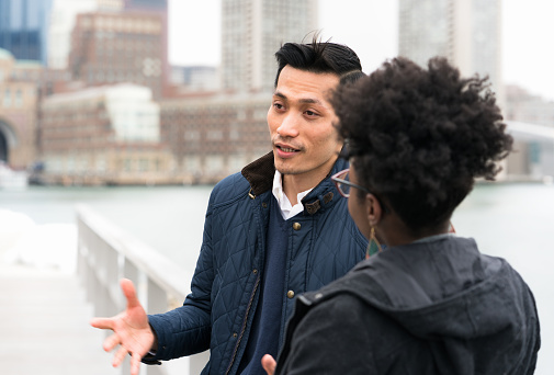 A man and a woman talking, with the city of Boston's skyline in the background.