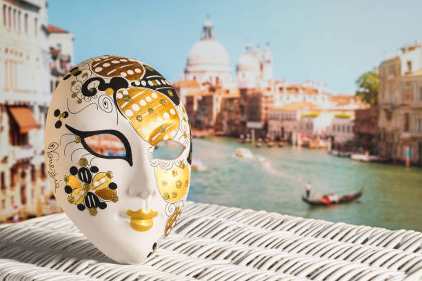 Venetian mask with Canal Grande and Santa Maria della Salute church in the background. Traditional souvenir and beautiful view to the city and a gondolier in a gondola. Sunny Venice. Travel concept gondola traditional boat photos stock pictures, royalty-free photos & images