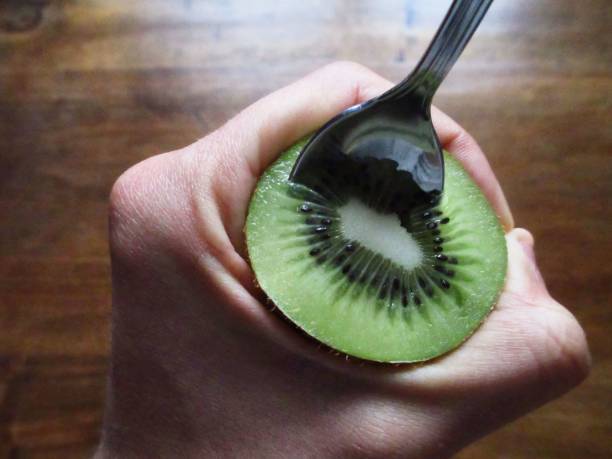 istock Human hand holding a kiwi fruit with a spoon 673437576