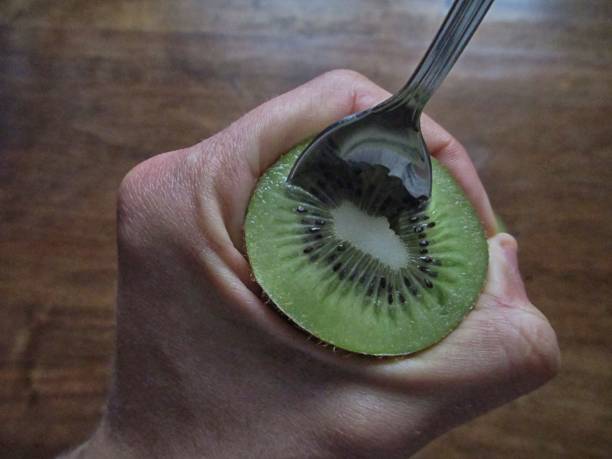 istock Human hand holding a kiwi fruit with a spoon 673442050