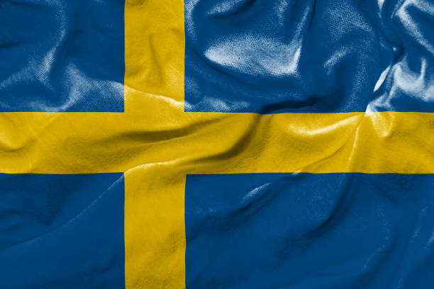 Sweden's flag blowing in the wind against a clear blue sky.