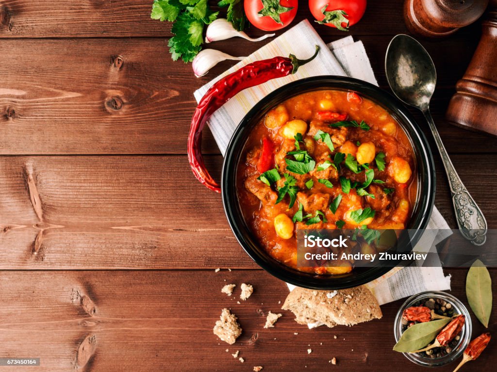 Goulash in ceramic bowl on wooden background. Traditional hungarian soup. Goulash in ceramic bowl on wooden background. Traditional hungarian soup. Rustic style. Top view. Goulash Stock Photo