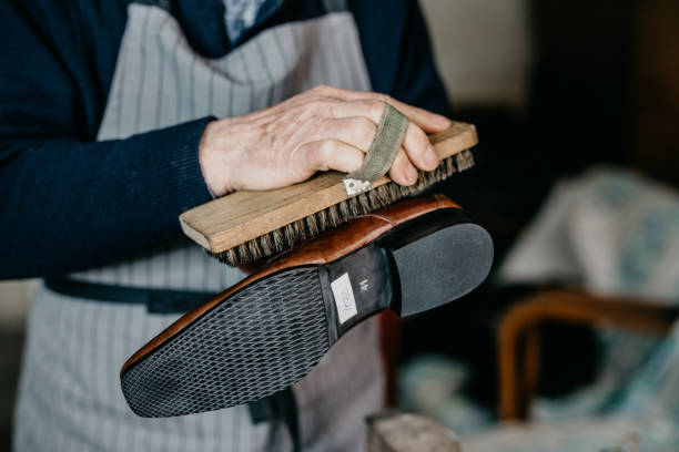 Old shoemaker is polishing a shoe Old shoemaker is polishing a shoe cobbler stock pictures, royalty-free photos & images