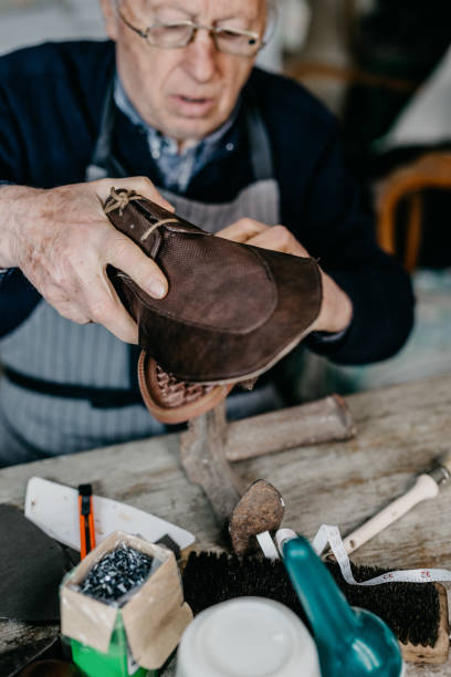 istock Old shoemaker making shoe at the shop 673450470