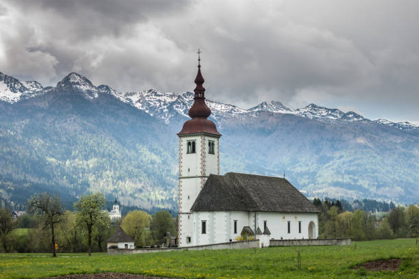 istock catholic church in field among Alps 673467926