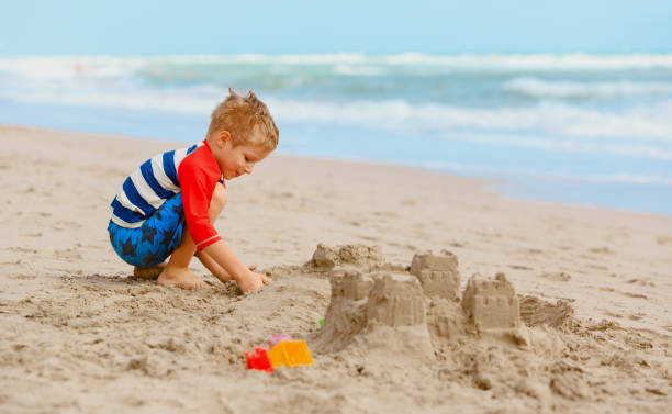 istock little boy play with sand on summer beach 673468828