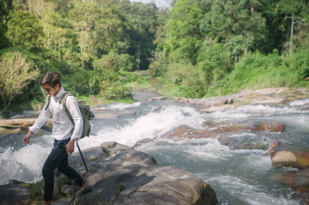 istock Businessman with backpack and laptop and phone at  waterfall  the forest. 673468998