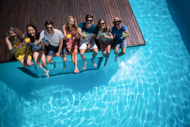 istock Happy friends sitting in swimming pool 673469026