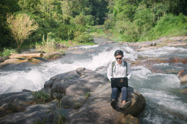 istock Businessman with backpack and laptop and phone at  waterfall  the forest. 673473466