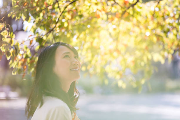 Young woman looking up under green leaves
