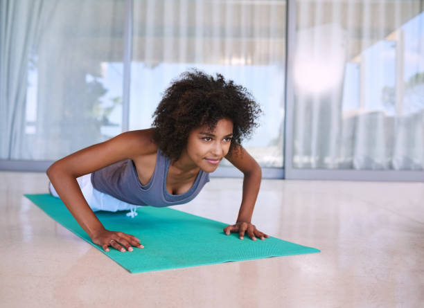 Getting stronger with each rep Shot of an attractive young woman doing push-ups on an exercise mat the black womens expo stock pictures, royalty-free photos & images