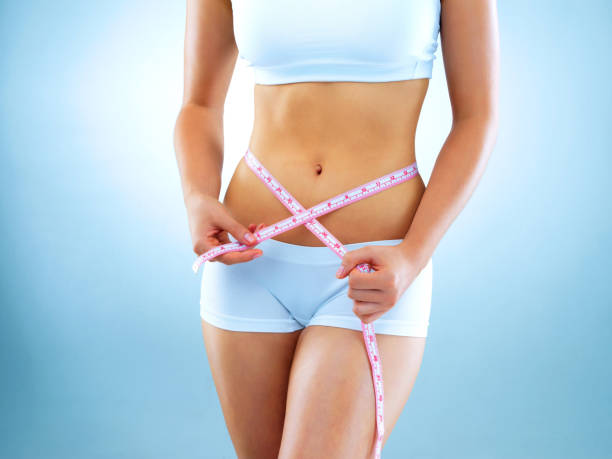 reaching weight loss goals one inch at a time - measuring waist imagens e fotografias de stock