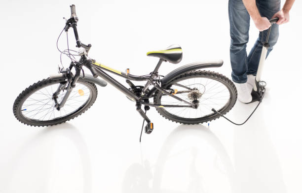 istock Low section of man inflating bicycle tire with pump on white 673494140