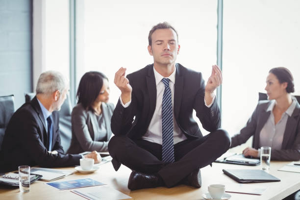 istock Businessman meditating in conference room 673500350