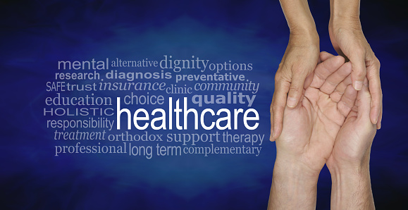 Female hands gently cradling male hands on a misty blue vignette background with a healthcare word cloud to the left