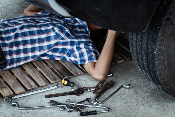 Little pretty girl is posing for photographer with tool at auto service workshop.