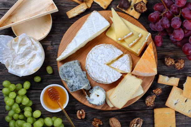 set of authentic french Cheese plate set of authentic french Cheese plate served with grapes, honey, homemade chocolate sweets and nuts on wooden round tray on dark wooden background, view from above auvergne rhône alpes photos stock pictures, royalty-free photos & images
