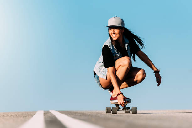 femme belle patineuse à cheval sur son longboard. - skate photos et images de collection