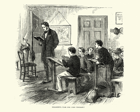 Vintage engraving of a victorian school classroom, with a boy in a dunce's cap standing behind the blackboard,  Leisure Hour, 1872