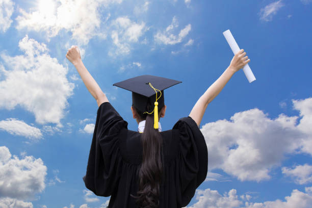 istock Graduate celebrating with certificate in her hand with blue sky background,Back of view 673571030