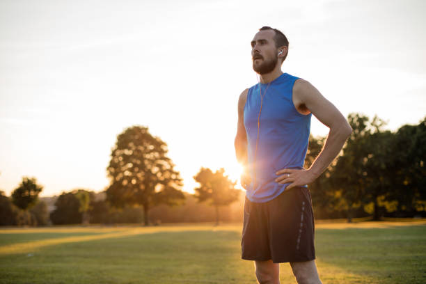 istock Young athletic man taking a post run break at sunset in the park 673574162
