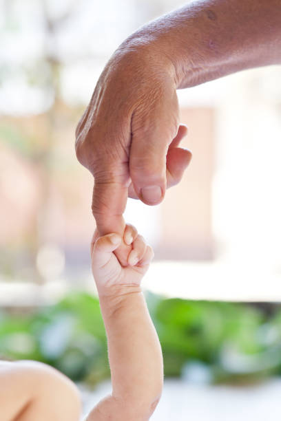 bambino che tiene il dito delle sue bisnonna dito. - multi generation family adoption family human hand foto e immagini stock