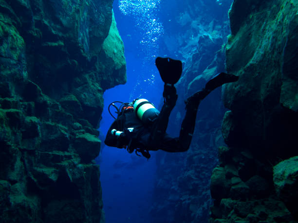 Scuba Diver with Buoyant Floating Feet Without Bubbles Inside Continental Split at Silfra in Deep Section at Pingvellir National Park Scuba Diving at Silfra, Iceland in Dry Suits at the Continental Divide at the Þingvellir National Park in Iceland. Glacial runoff water (fresh water). 0 Celsius. scuba diver point of view stock pictures, royalty-free photos & images