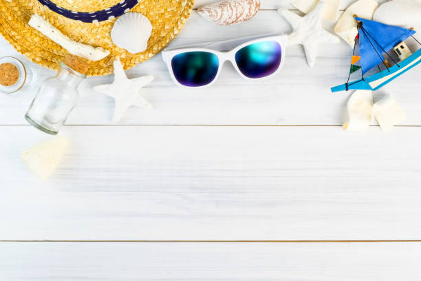 Summer Beach accessories (White sunglasses,starfish,straw hat,glass bottle,shell) on white plaster wood table top view,Summer vacation concept,Leave space for adding text.