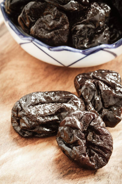 istock dried plums prunes on wooden table 673598004