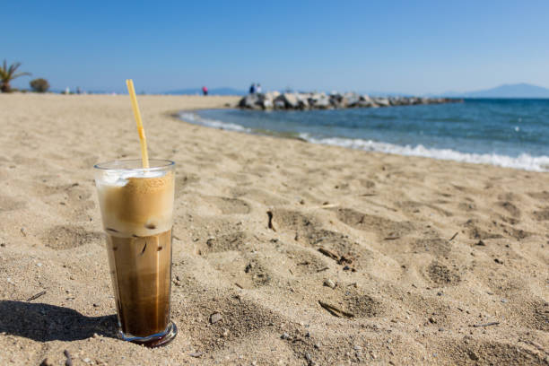 Freddo cappuccino on the beach. Freddo cappuccino coffee on a transparnt glass placed on the sand, beach background. freddo cappuccino stock pictures, royalty-free photos & images