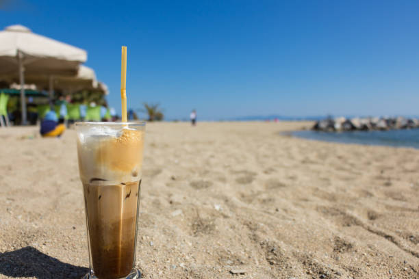 Freddo cappuccino on the beach. Freddo cappuccino coffee on a transparnt glass placed on the sand, beach background. freddo cappuccino stock pictures, royalty-free photos & images