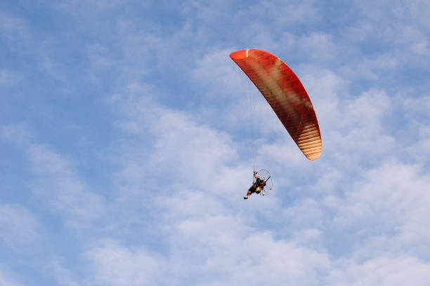 istock Orange parachute flying in a blue sky 673617646