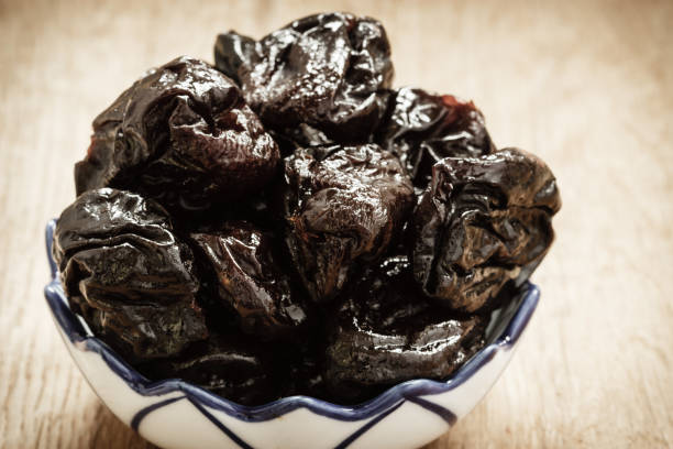 istock dried plums prunes in bowl on wooden table 673618334