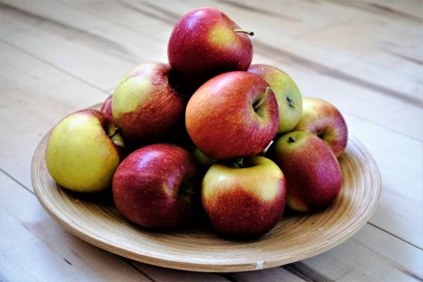 istock Apples in a bowl on wooden floor 673620952