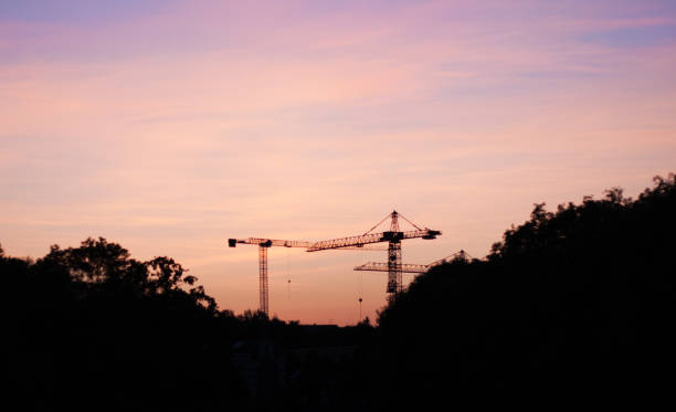 Tower cranes against the background of a bright sunset. Colorful sky over the city. Building on a beautiful bright background