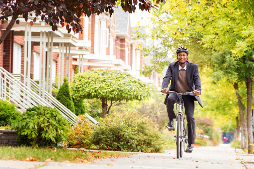 Single black male in his 30s cycling on urban sidewalk in Autumn