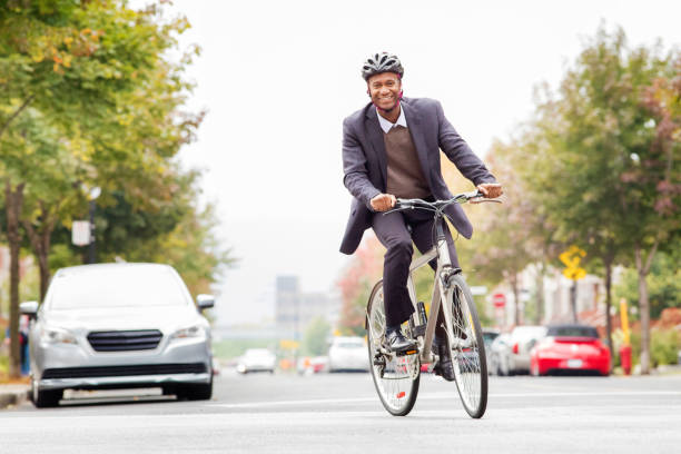 único hombre negro en sus 30s sonriendo mientras viaja al trabajo en bicicleta - african descent cycling men bicycle fotografías e imágenes de stock