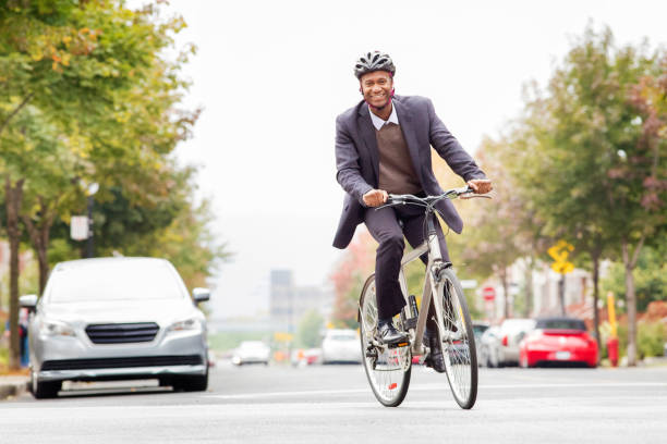 одинокий черный мужчина в возрасте 30 лет улыбается, когда ездит на работу на велосипеде - city street montreal street city стоковые фото и изображения