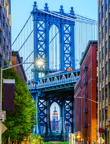 The Empire State Building can be seen under the Manhattan Bridge at the Brooklyn Bridge Park, New York City, New York. The street, the bridge and the Empire State Building is aligned perfect.