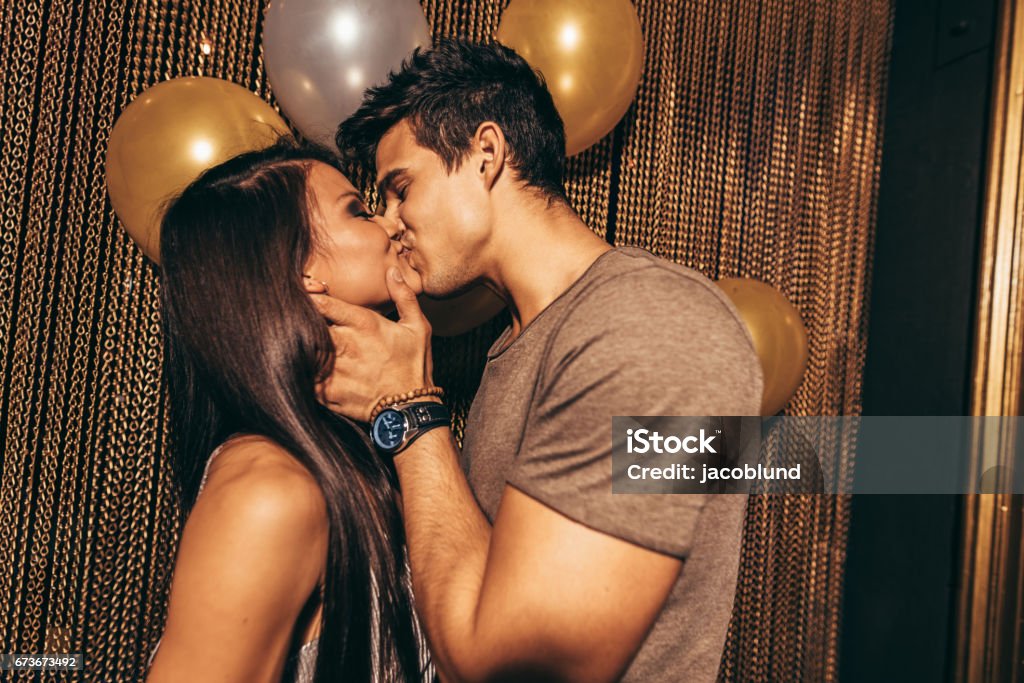 Romantic young couple kissing in the night club Shot of romantic young couple kissing in the night club. Man and woman in the pub. Kissing Stock Photo