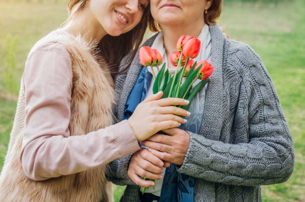 istock Middle-aged mother and her daughter hugging in blooming garden 673674080