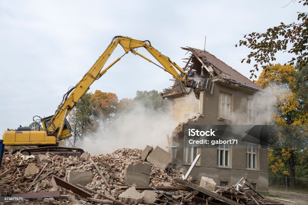 digger demolishing houses A digger demolishing houses for reconstruction. Demolishing Stock Photo
