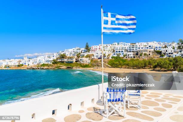 Greek Flag Waving On A Terrace Overlooking Piperi Beach In Naoussa Village Paros Island Cyclades Greece Stock Photo - Download Image Now