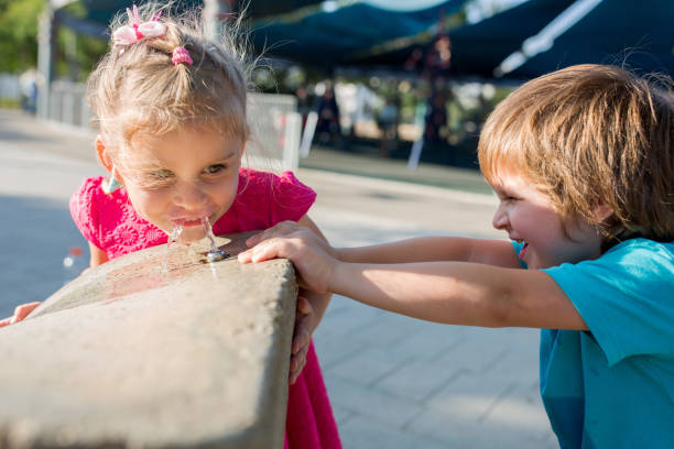 istock Small girl drinking water from a fountain. 673684294