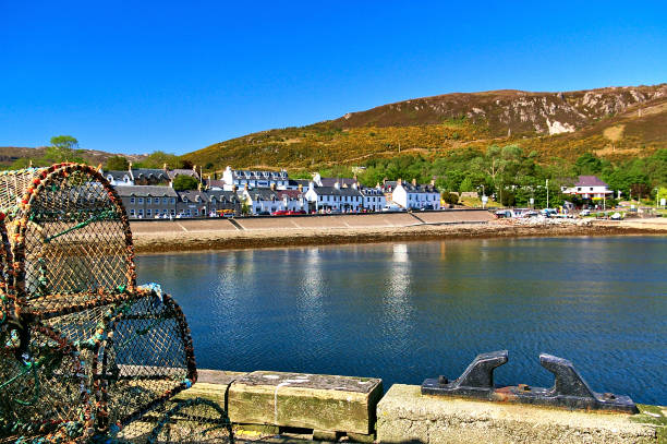 Quay with fish traps and bollard in the foreground and white waterfront houses in the background stock photo