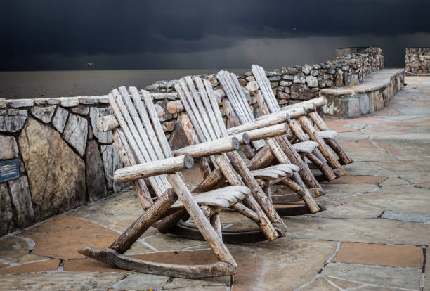 istock wood chairs sitting on stone walkway with storm clouds brewing 673688062