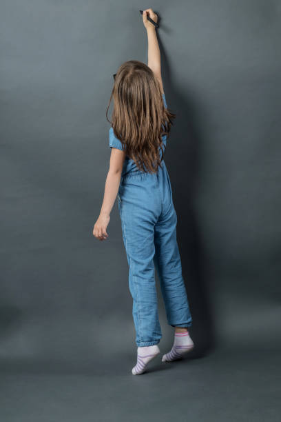 istock young girl on tiptoe writing at grey background 673704438