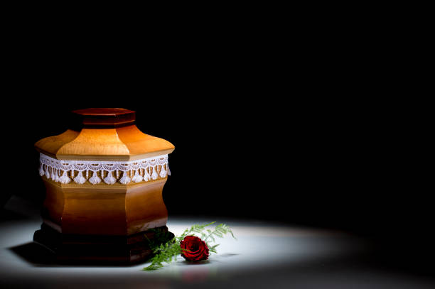 istock Wooden cemetery urn with red rose 673710548