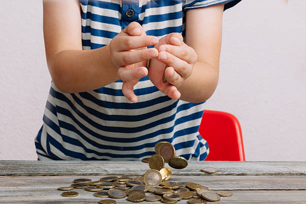 midsection of boy playing with coins on table against white background - elementary age focus on foreground indoors studio shot imagens e fotografias de stock