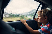 Little boy travelling in car on a rainy day